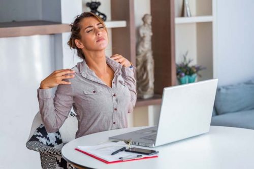 Stressed woman suffering from back pain after working on pc