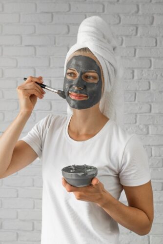 FREEPIK - woman applying a charcoal mask to her face. 